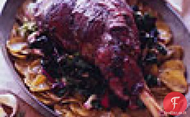 Coscia di agnello arrosto su un letto di patate e verdure appassite
