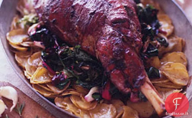 Coscia di agnello arrosto su un letto di patate e verdure appassite