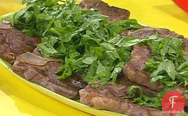Bistecche di T-Bone con Garni verdi tritati, pomodori alla griglia con formaggio, olive ed erbe aromatiche