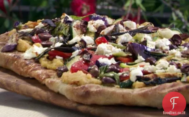 Pizza alla griglia con Hummus piccante, verdure, formaggio di capra e olive nere